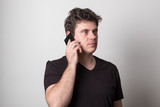 Man is talking on a cell phone. Smiling young man in a black T-shirt talking on the phone.