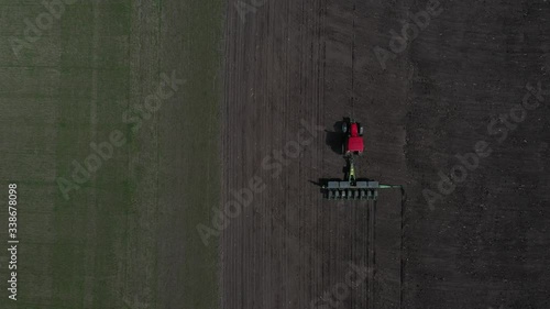 Top view of a spacious meadow getting scattered with seeds by a combine . Agriculture, tractor plow the earth in field, view from height.