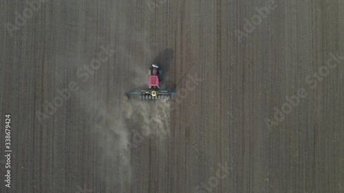 Top view of a spacious meadow getting scattered with seeds by a combine . Agriculture, tractor plow the earth in field, view from height.