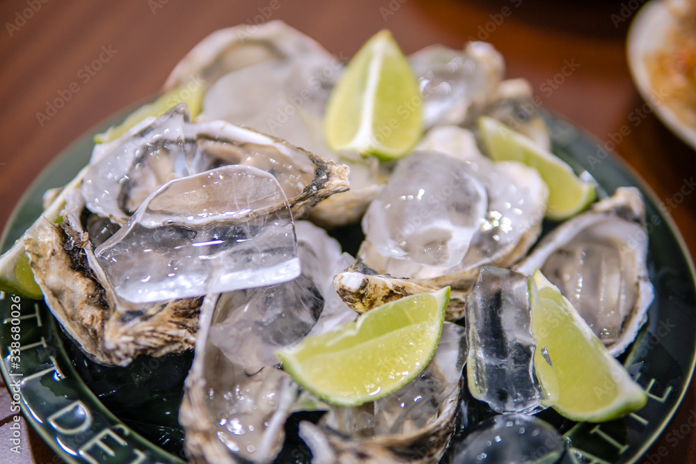 Oysters platter with lemon and ice served on dish