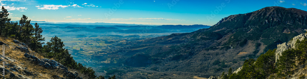 Panorama of the beautiful Vipava valley in the january sun looking from the Otlica plateau. Visible winter fog in the valley and the town of Lokavec at the bottom.