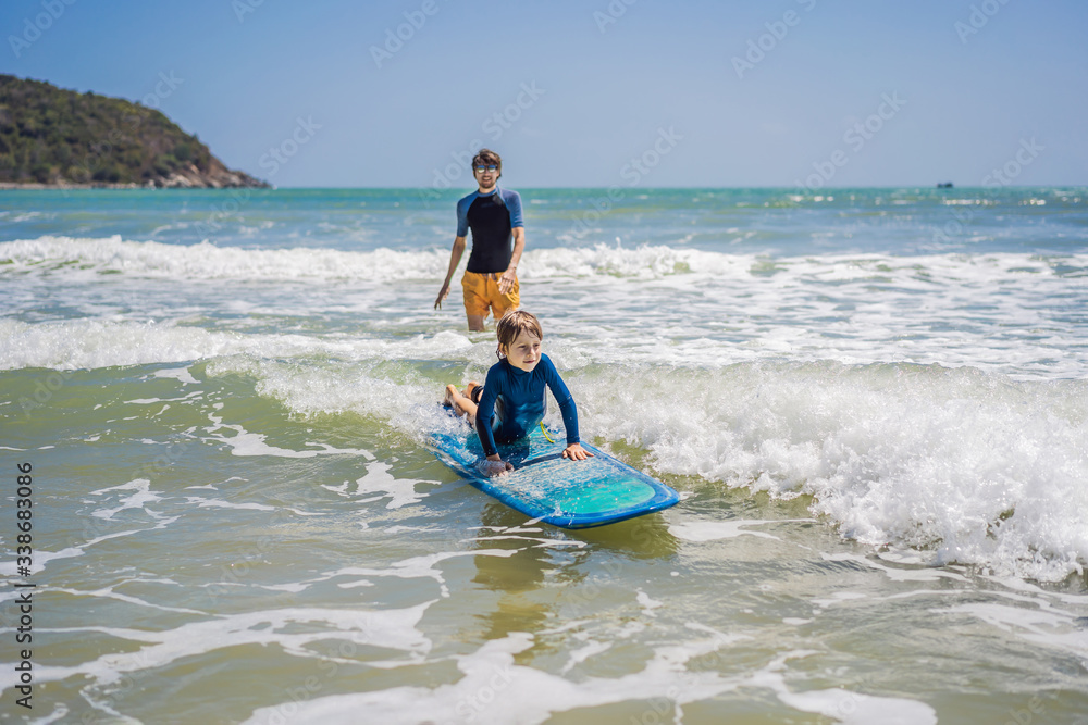 Father or instructor teaching his son how to surf in the sea on vacation or holiday. Travel and sports with children concept. Surfing lesson for kids Father or instructor teaching his son how to surf in the sea on vacation or holiday. Travel and sports with children concept. Surfing lesson for kids