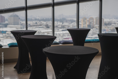 фотографія Multitude of empty elegant black standing tables for lunch reception with a nice view behind over the city blocks