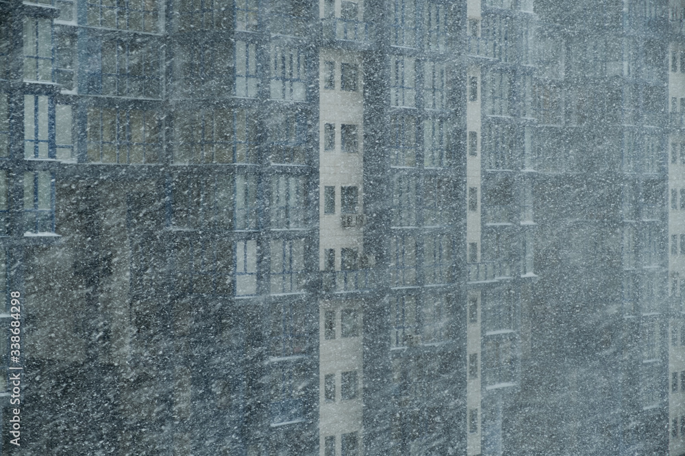 Winter snowfall on the background of a multi-storey building.