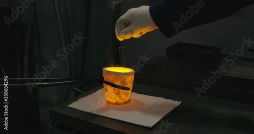 Worker puts the powder to hot liquid molten gold. RED Camera, 4k photo