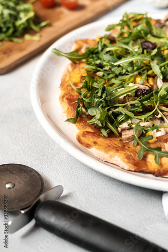Vegan pizza with vegetables and arugula.