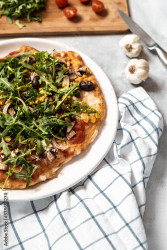 Vegan pizza with vegetables and arugula.