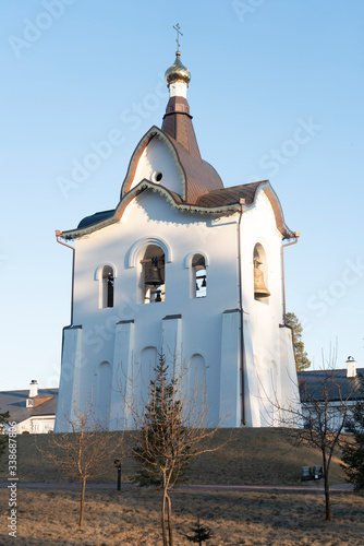 White church bell tower with a bronze roof and a golden dome.