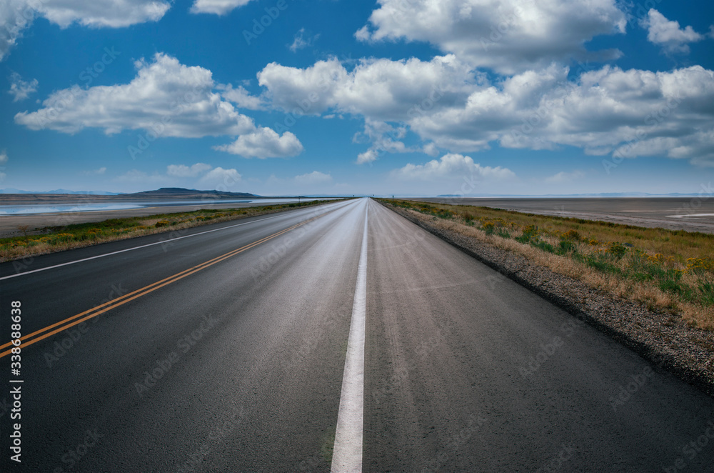 Autostrada verso l'orizzonte con cielo azzurro e qualche nuvola