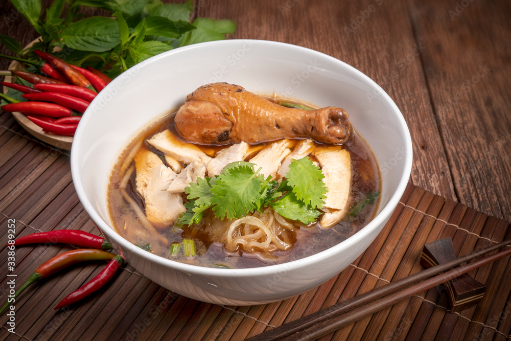 Chicken noodle soup on wood table, Chicken soup with noodles and vegetables in bowl over rustic wooden background Chicken noodle soup on wood table, Chicken soup with noodles and vegetables in bowl over rustic wooden background