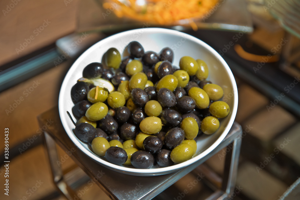 Top view with space for text . Green and black olives in a white ceramic bowl . Top view with space for text . Green and black olives in a white ceramic bowl .