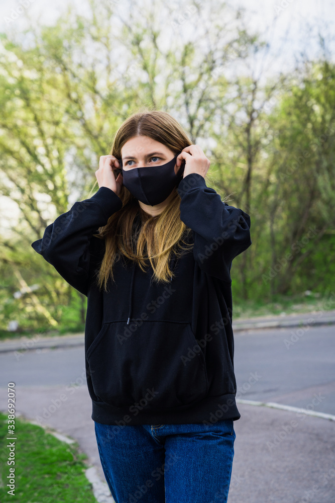 White woman in a park wearing black protective mask. coronavirus protective mask. Outside home White woman in a park wearing black protective mask. coronavirus protective mask. Outside home