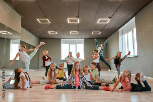 Fototapeta Naklejka Na Ścianę i Meble -  Keep dancing. Group of happy little boys and girls in fashionable clothes posing together in the dance studio. Dance team.