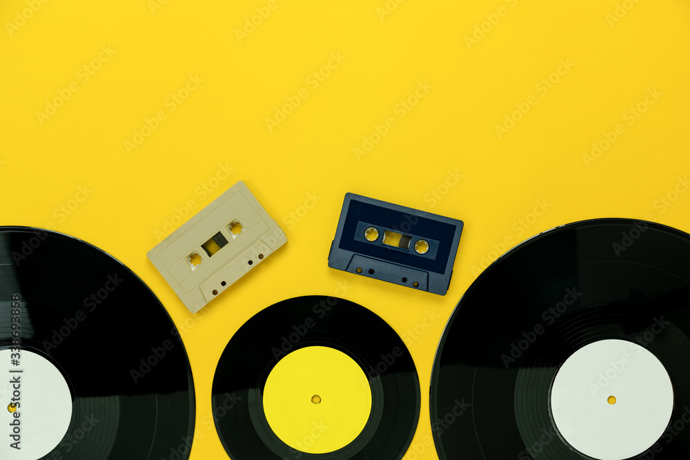Obraz premium Table Top view of musical instrument retro concept.Flat lay objects of the many music disk and cassette tape on modern rustic yellow paper at home office desk.copy space for creative design text.