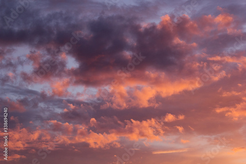 Lovely golden, purple and pink clouds in blue heaven with soft haze on sunset as abstract background, texture.