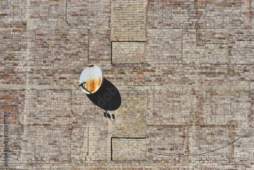 Rusty satellite dish hanging on old brick wall