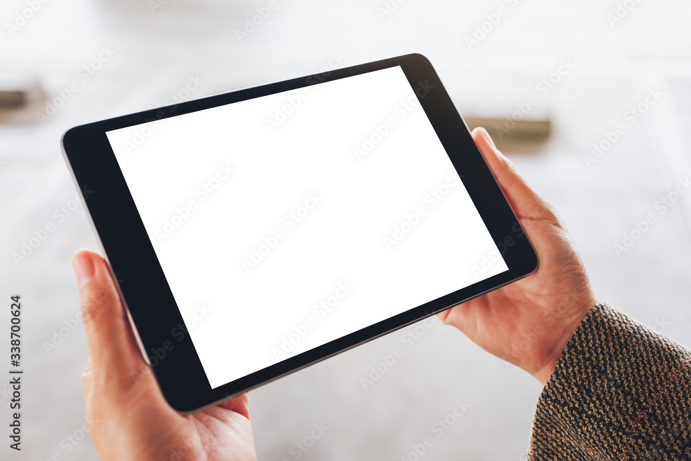 Mockup image of a woman holding black tablet pc with blank white screen on the street