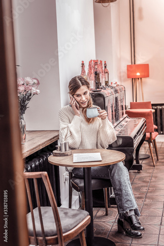 Gorgeous young woman sitting at cafe drinking coffee