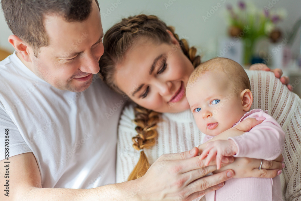 Beautiful young parents are holding their little newborn daughter in their arms. Blue-eyed little girl of 2 months. Baby Beautiful young parents are holding their little newborn daughter in their arms. Blue-eyed little girl of 2 months. Baby