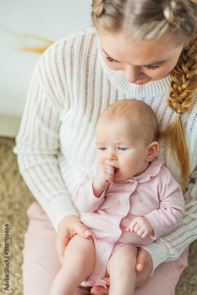 A beautiful young mother holds in her arms a small pretty blue-eyed 2-month-old daughter. Newborn. A beautiful young mother holds in her arms a small pretty blue-eyed 2-month-old daughter. Newborn.