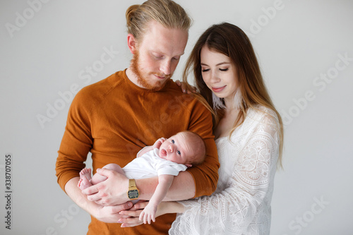 Parenthood, love and family concept - Smiling mother and father holding their baby son.Happy European family, father mother and son baby. Young parents with a newborn son in their arms in the Studio o