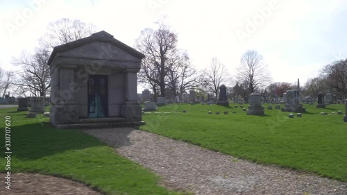 SLOW MOTION (48FPS): Driving slowly by an old mausoleum and rows of old headstones through a cemetery on a beautiful day