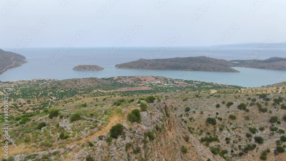 Aerial flying over a mount near Spinalonga island with the sea on background Aerial flying over a mount near Spinalonga island with the sea on background