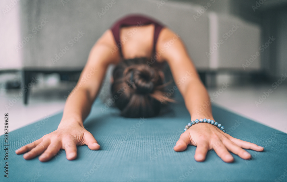 © Maridav - Yoga home stretching meditation woman doing childs pose warm up stretch in living room home. Hands touching floor exercise mat and mala bracelet. Fitness relaxation stress- free concept.