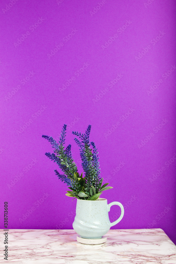 Lavender flowers in a mug on a marble table and purple background Lavender flowers in a mug on a marble table and purple background