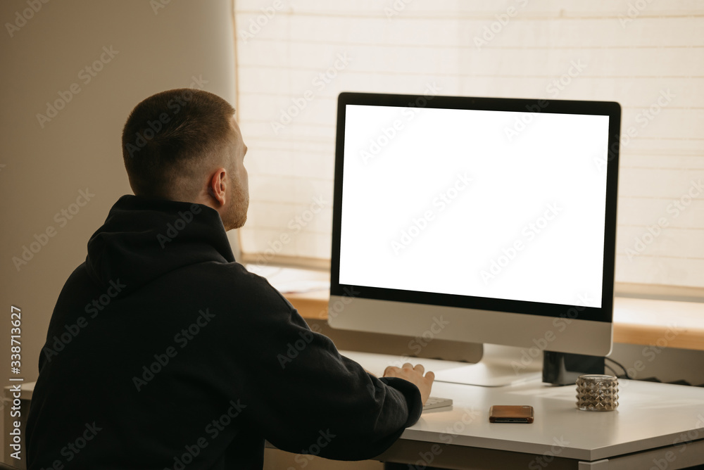 Remote work. A back view of a businessman works remotely using an all-in-one computer. A fellow working from home. Remote work. A back view of a businessman works remotely using an all-in-one computer. A fellow working from home.