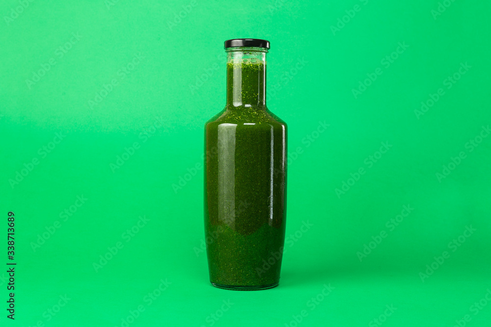 Fresh celery spinach juice in a glass bottle isolated on green background. Healthy eating Detox juice diet. Fresh celery spinach juice in a glass bottle isolated on green background. Healthy eating Detox juice diet.