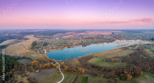 Spring rural landscape in the evening. Aerial view. Panoramic view of the lake, village, and fields. Panorama from 9 images