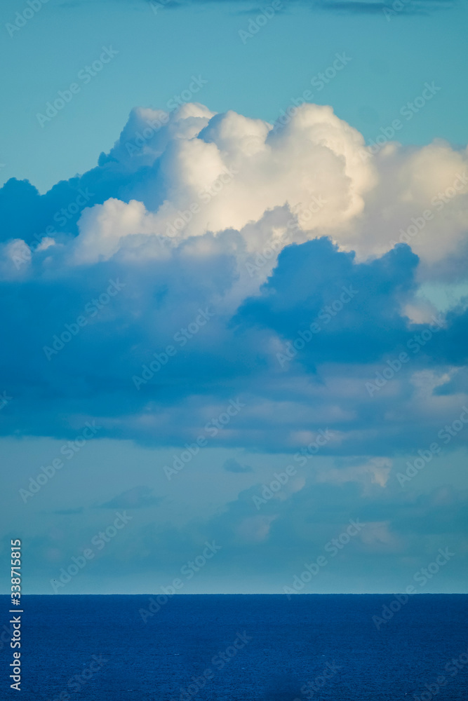 Beautiful blue coloured background of sea ocean water and horizon line with white clouds in the sky - concept of travel and nature