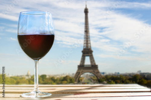 Glass of wine on Eiffel tower blur background. Sunny view of glass of red wine overlooking the Eiffel Tower in Paris  France
