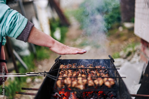 Woman's hand checks the heat of the grill with barbecue.