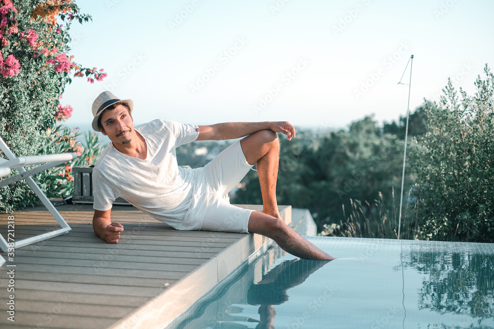 Ethnic Stylish young man lying near a swimming pool