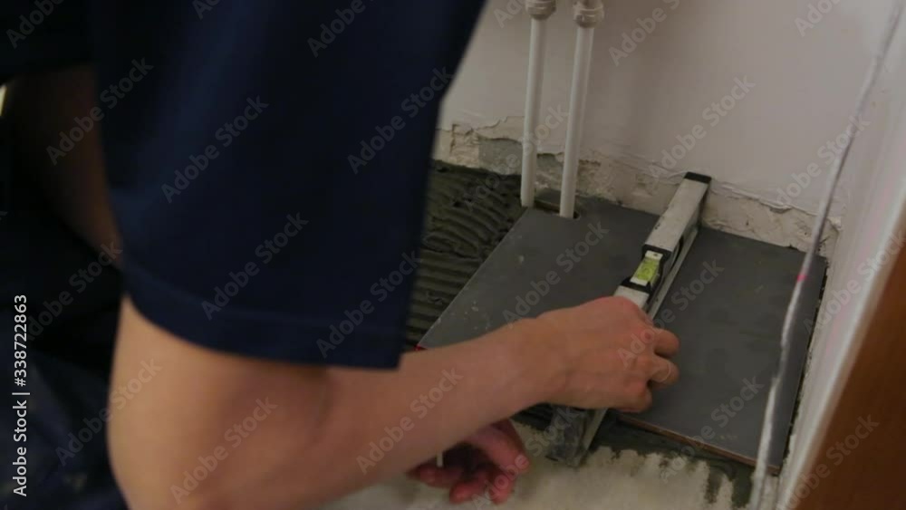 Worker checking level laying tiles on the floor Worker checking level laying tiles on the floor