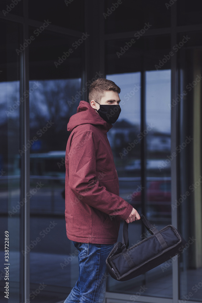 young male food delivery man with a black bag and a mask. online food delivery during quarantine young male food delivery man with a black bag and a mask. online food delivery during quarantine