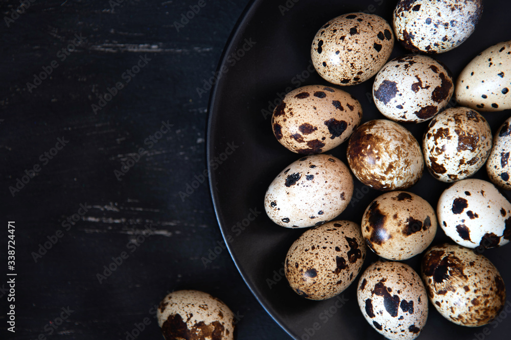 Quail eggs in a black plate. On the old background. Top view. Free copy space