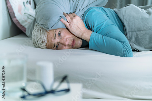 Hyperacusis Disorder.  Mature Woman Suffering From Hyperacusis, Fear of Sounds Holding Pillow Over Her Head photo