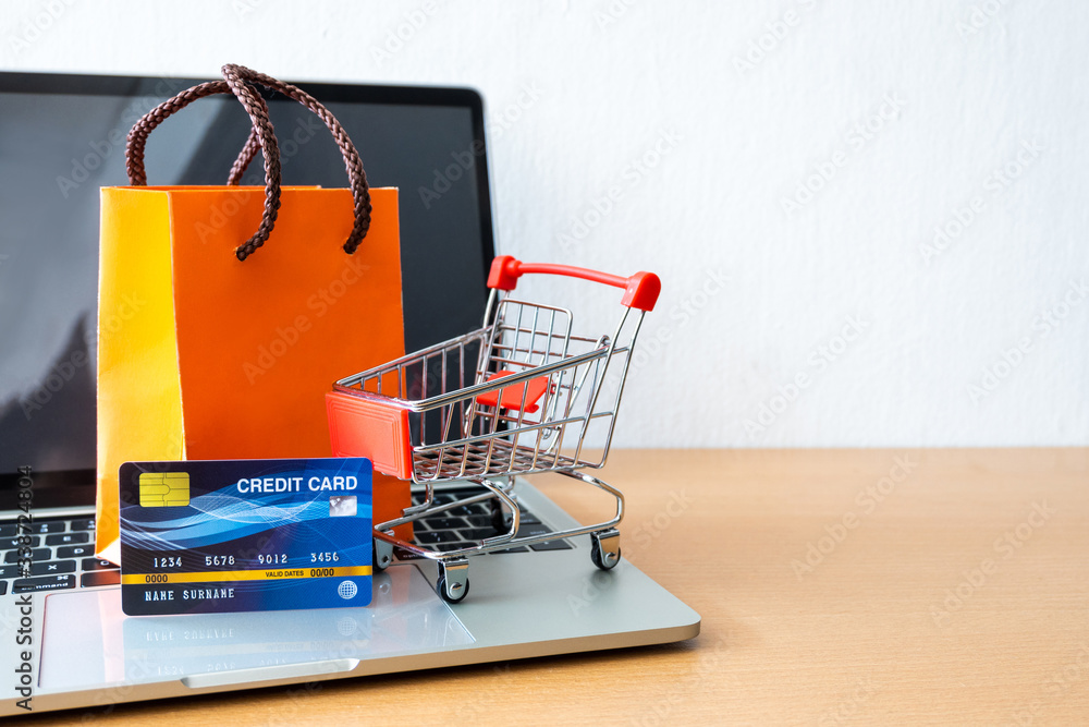 credit card and cart supermarket and orange paper bag on wood table. shopping concept