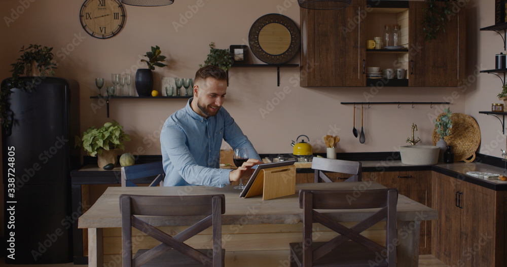 Handsome Caucasian man having a glass of wine during video call with friends or partner. Stay home, quarantine life Handsome Caucasian man having a glass of wine during video call with friends or partner. Stay home, quarantine life