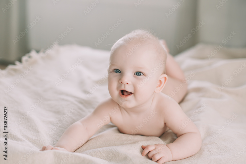 Healthy baby in bed. Cute happy baby girl sitting and playing. A portrait of a beautiful baby girl. Childhood, baby care concept Healthy baby in bed. Cute happy baby girl sitting and playing. A portrait of a beautiful baby girl. Childhood, baby care concept