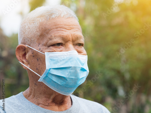 Portrait of elderly man with short white hair, wearing face mask for health because have air pollution PM 2.5. Mask for protect virus, coronavirus, bacteria, pollen grains. Health care concept