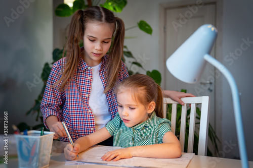 older sister helps younger with their writings