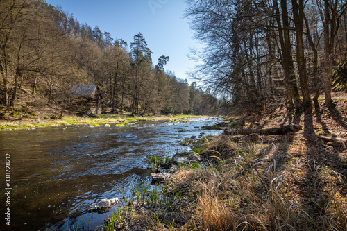 Romantic spring river valley with old cabin under blue sky