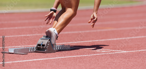 Fototapeta Athlete female feet on starting block ready for a sprint start