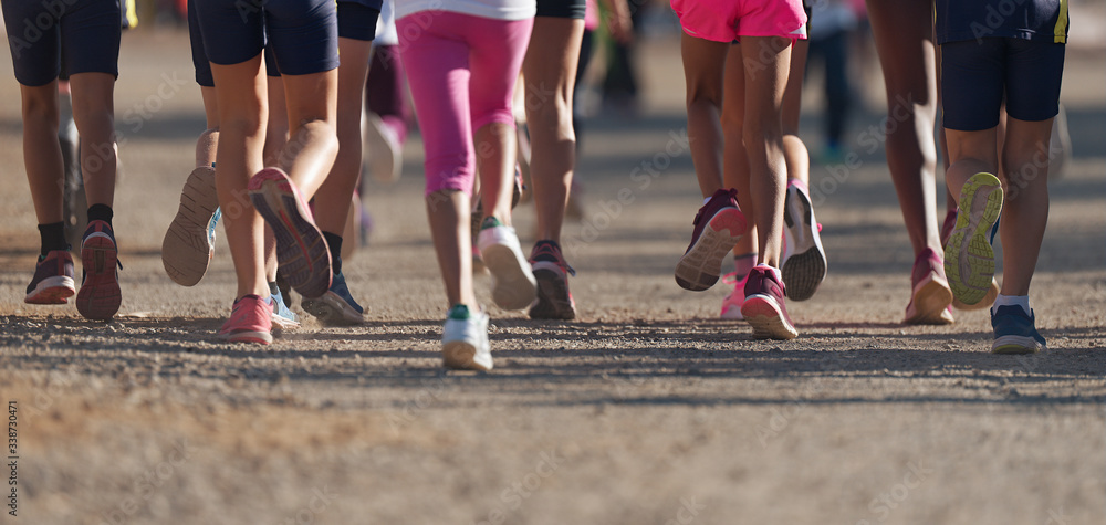 Running children, young athletes running in a kids run race, running on a park road detail on legs, running in the light of morning Running children, young athletes running in a kids run race, running on a park road detail on legs, running in the light of morning