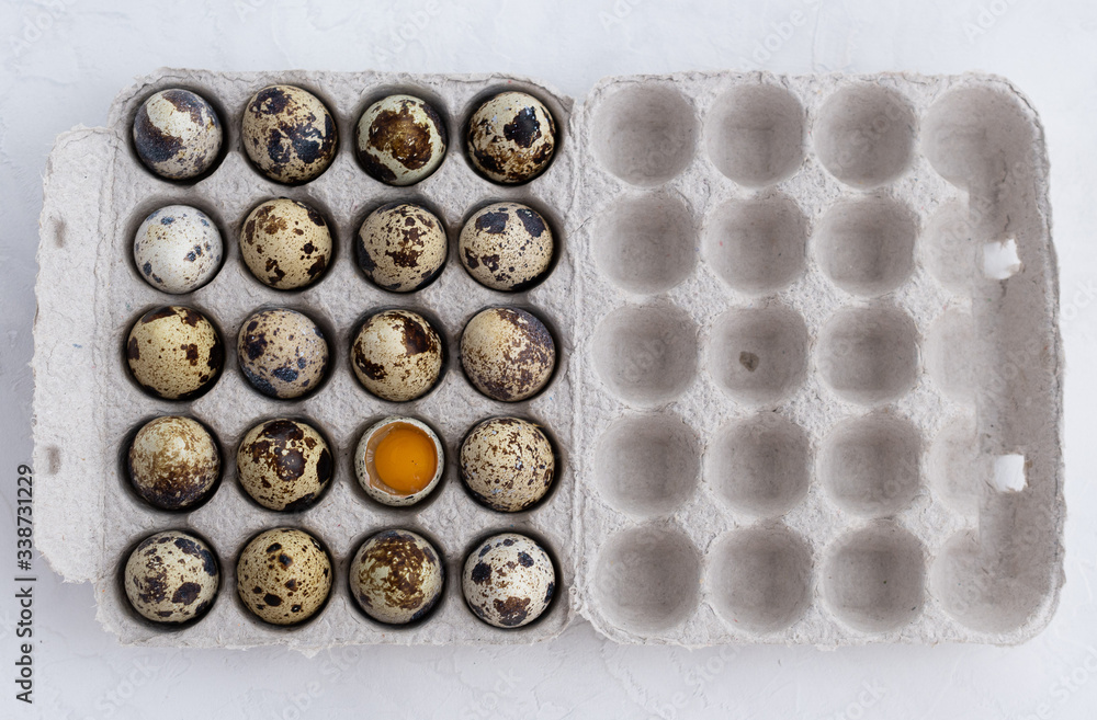 Quail eggs in paper packaging with one broken egg Quail eggs in paper packaging with one broken egg