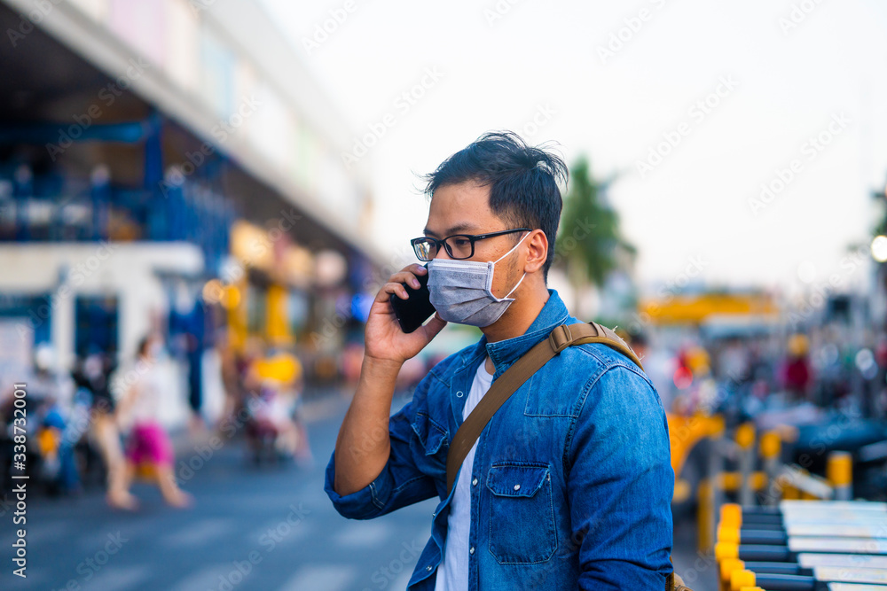 Concept, diseases, viruses, allergies, air pollution. Portrait of Man wearing surgical mask on street while using phone. The image face of a young man wearing a mask to prevent germs, toxic fumes... Concept, diseases, viruses, allergies, air pollution. Portrait of Man wearing surgical mask on street while using phone. The image face of a young man wearing a mask to prevent germs, toxic fumes...